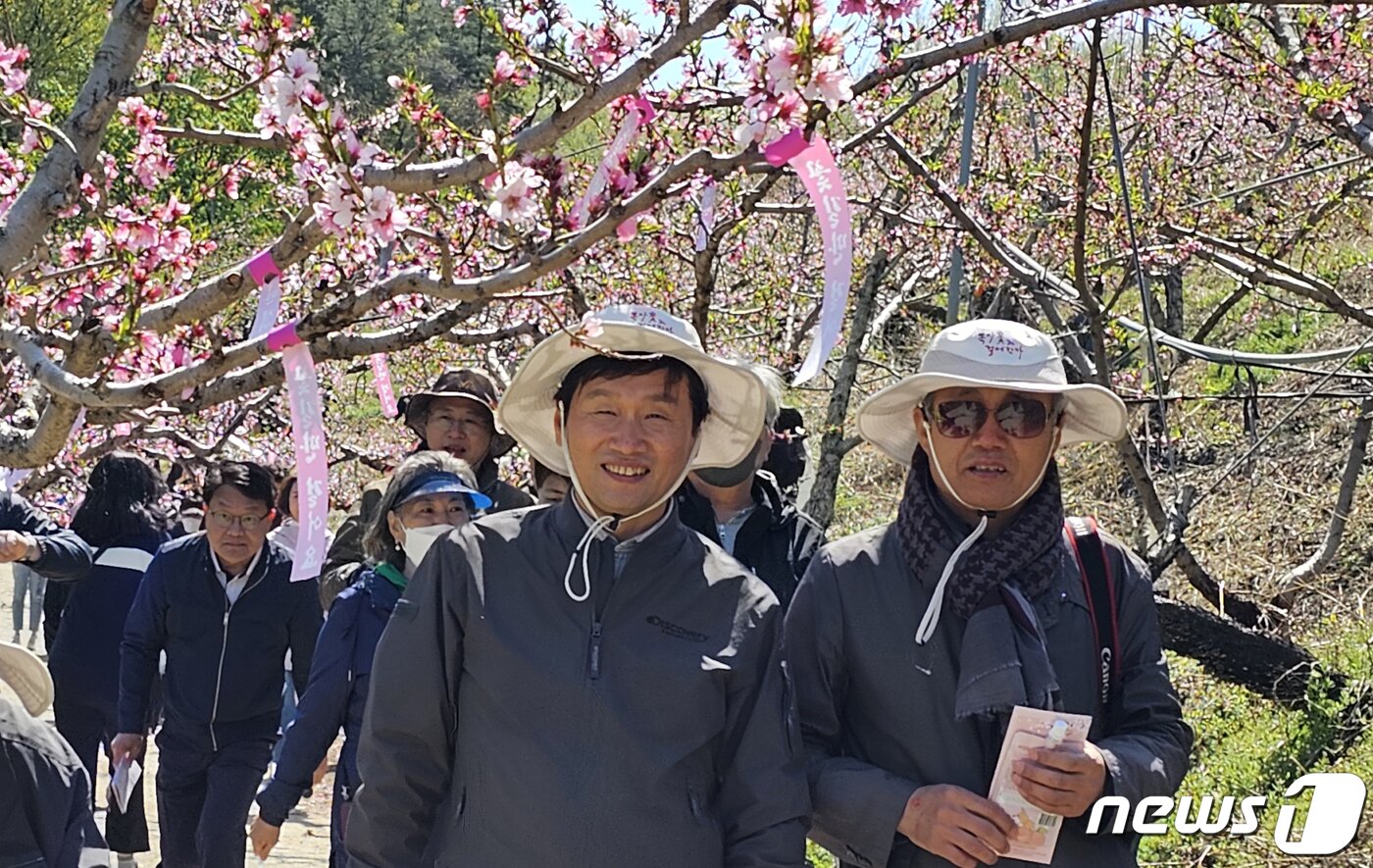 본문 이미지 - 8일 경북 경산시 남산면 반곡지 일원에서 열린 '복사꽃길 걷기'행사에서 조현일 경산시장(왼쪽)이 복사꽃이 만발한 밭 사이로 걷고 있다. 반곡지는 수백년된 왕버들 20여 그루가 줄지어 선 나무터널이 문화체육관광부 '사진찍기 좋은 녹색명소'로 선정된 곳이다. 2023.4.8/뉴스1 ⓒ News1 정우용 기자