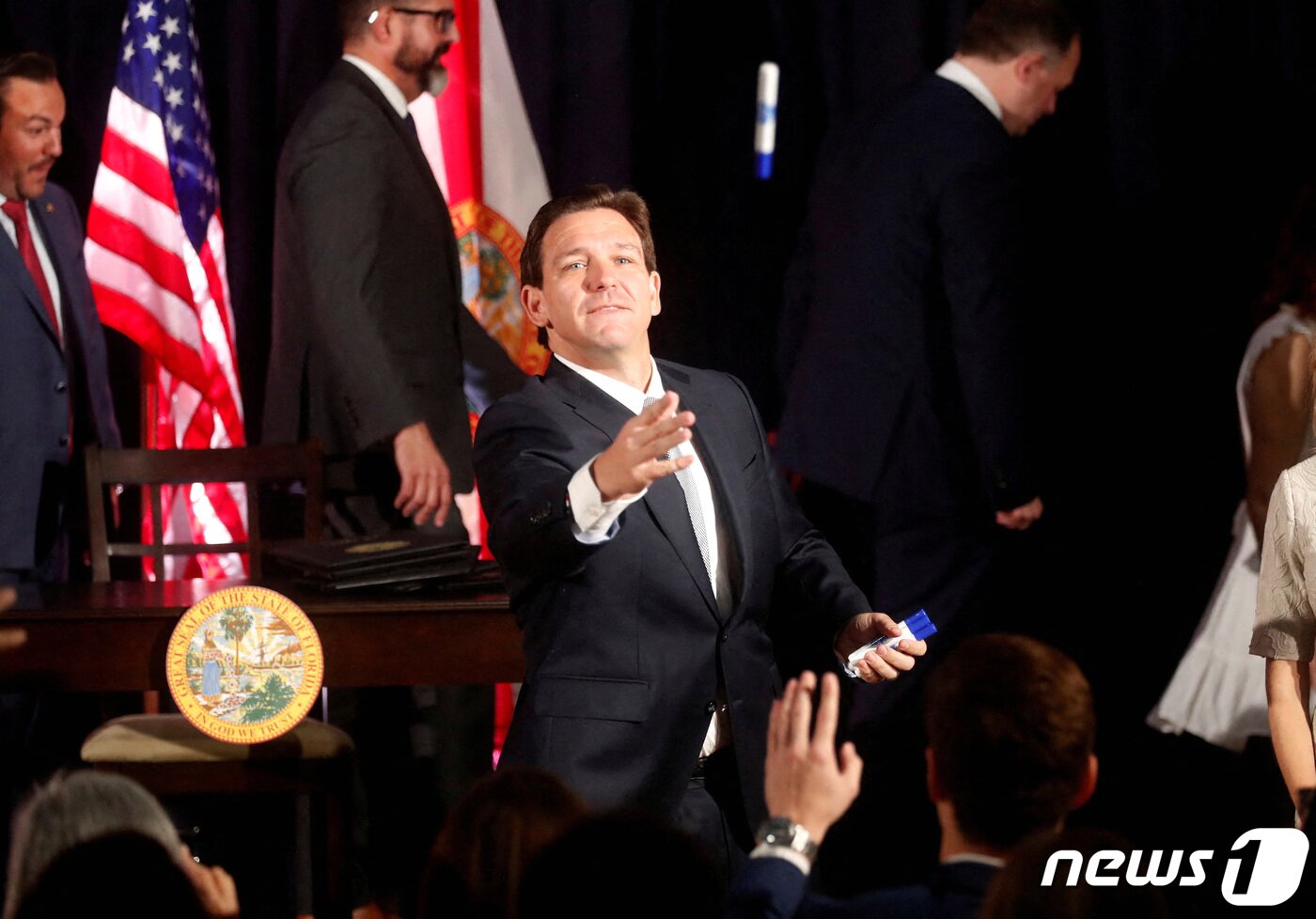 본문 이미지 - 17일(현지시간) 미국 플로리다주 템파의 한 초등학교에서 기자회견 중인 론 디샌티스 플로리다 주지사가 학생들에게 펜을 던지고 있다. 2023.5.17 ⓒ 로이터=뉴스1 ⓒ News1 정윤미 기자