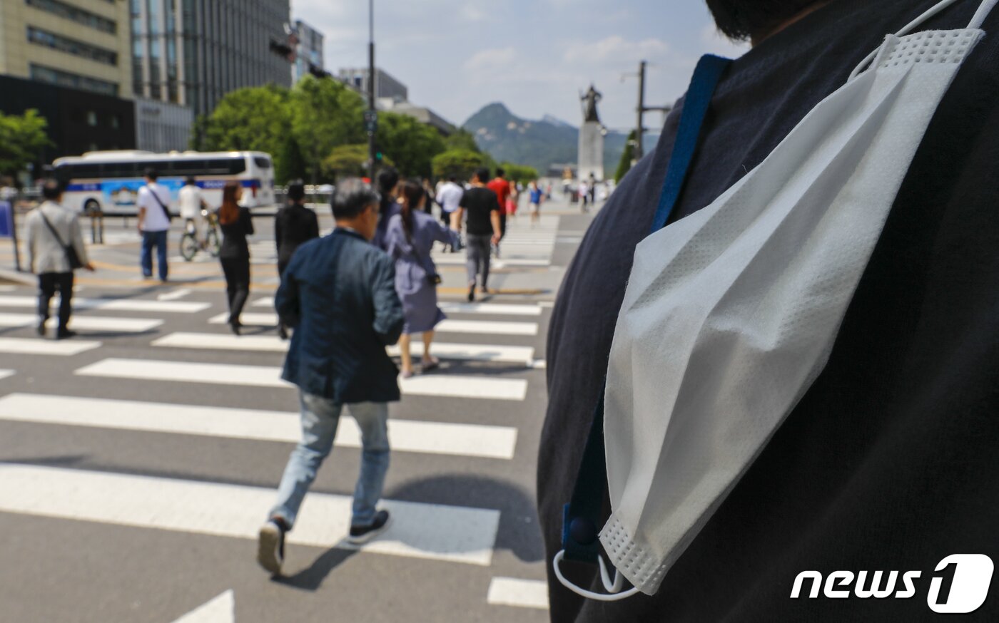본문 이미지 - 31일 서울 광화문네거리를 지나는 한 시민이 마스크를 벗고 있다. 정부는 6월 1일부터 신종 코로나바이러스 감염증(코로나19) 감염병 위기 경보 단계를 '심각'에서 '경계'로 내리고, 확진자에 대한 격리 의무폐지, 임시 선별검사소 운영종료 등 방역조치를 완화한다. 2023.5.31/뉴스1 ⓒ News1 김도우 기자