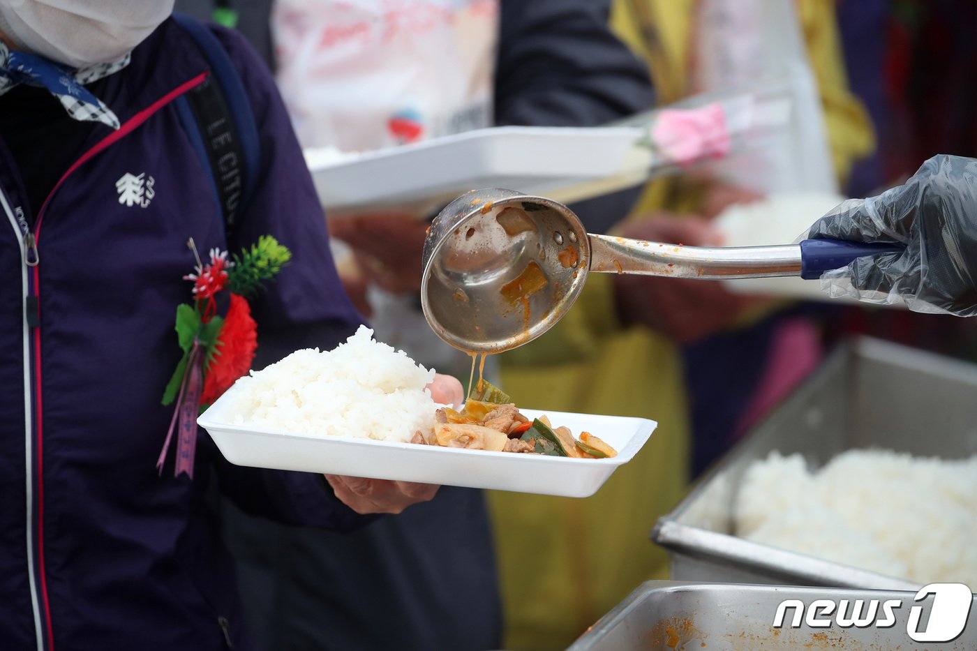 어버이날인 8일 오전 대구 달서구 두류공원 사랑해밥차 무료급식소를 찾은 노인들이 점심 배식을 받고 있다. 가슴에는 자원봉사자들이 선물한 카네이션이 달려 있다. 코로나19 사태 이후 후원이 줄어들어 무료급식소 운영에 어려움을 겪는 가운데 이날 어버이날을 맞아 한 노무법인의 후원으로 1200여명에게 무료급식과 함께 카네이션과 작은 선물을 나눠줬다.  기사 내용과 관련 없음. 2023.5.8/뉴스1 ⓒ News1 공정식 기자