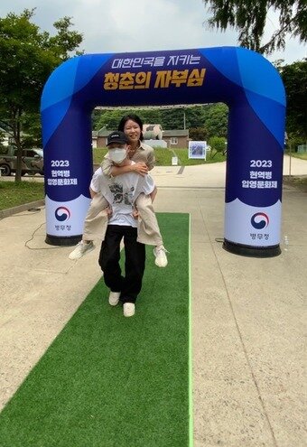 본문 이미지 -  권유진씨(50·여)가 아들 오재혁씨(21)의 등에 업혀 '어부바길'을 지나고 있다.(병무청 제공)