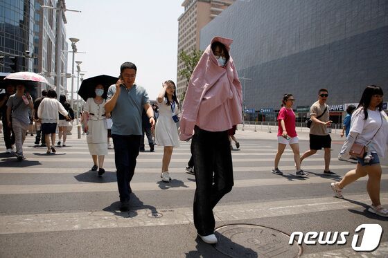 16일 중국 베이징에서 폭염 경보가 발령된 가운데 한 시민이 햇빛을 가리기 위해 옷으로 상체를 덮은 채 이동하고 있다. 2023.06.16 © 로이터=뉴스1 © News1 최종일 기자