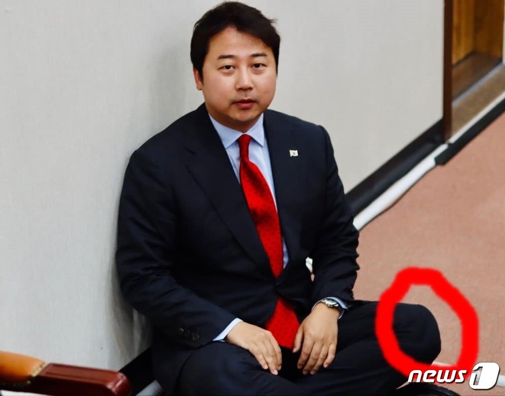 본문 이미지 -  장예찬 국민의힘 최고위원은 지난 15일 최고위원회 회의 도중, 무릎보호대(붉은 원)를 차고도 얼마든지 양반다리 자세를 할 수 있다는 것을 보여주기 위해 맨바닥에 주저앉았다. 이는 장경태 더불어민주당 의원이 방통위 항의방문 도중 실신한 것에해 '무릎 보호대를 차고 실신쇼를 연출한 것 아니냐'는 의혹 제기 차원이다. (장예찬 SNS 갈무리) ⓒ 뉴스1