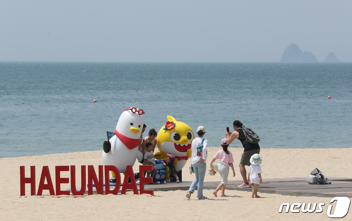 (부산=뉴스1) 윤일지 기자 = 19일 외국인 관광객들이 부산 해운대해수욕장에 설치된 부산시 홍보 캐릭터 '부기'와 2030부산세계박람회 제5호 홍보대사인 '핑크퐁 아기상어' 조형 …