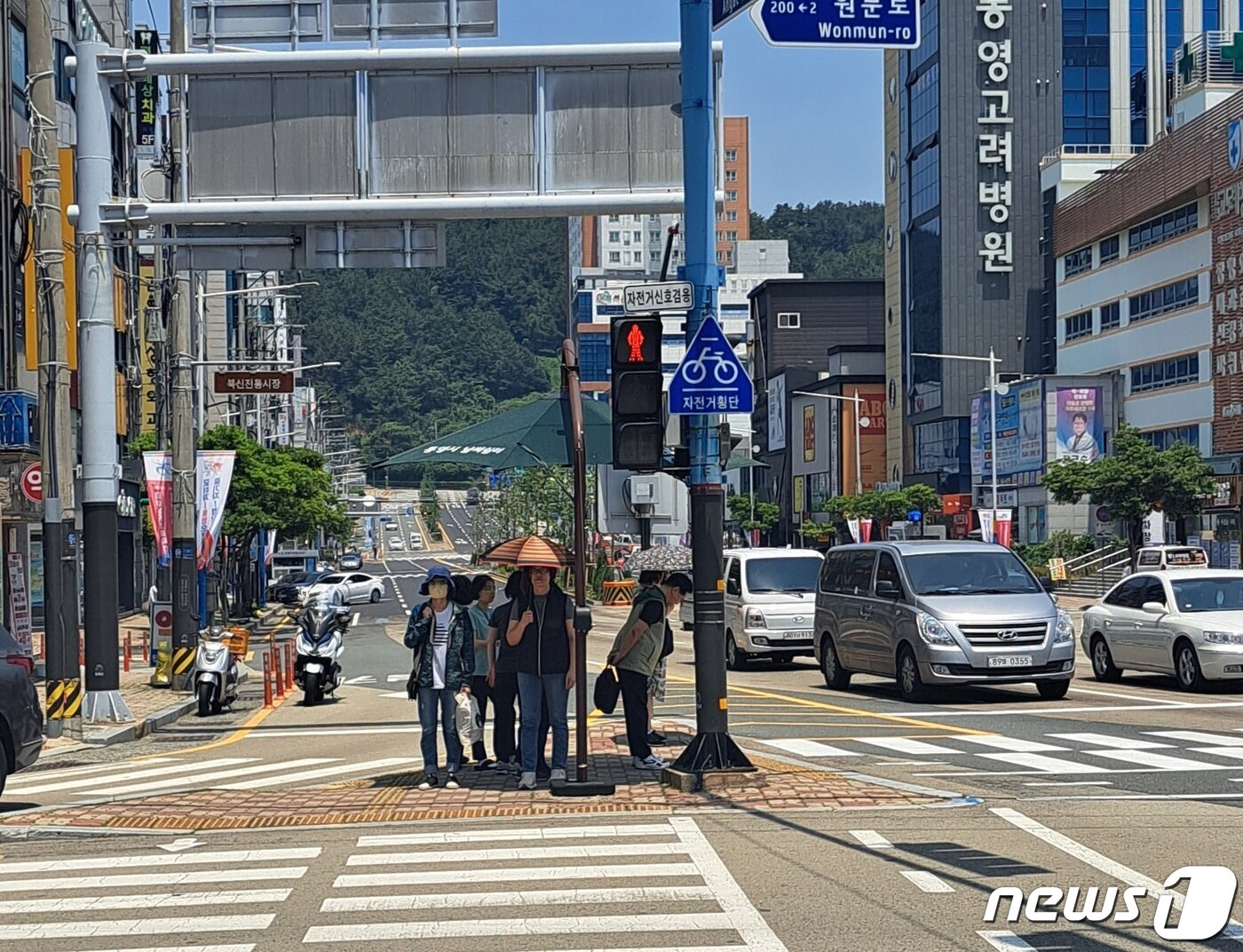 본문 이미지 - 19일 낮 경남 통영시 무전동 무전사거리 횡단보도 앞 인도에 설치된 그늘막 아래에서 시민들이 햇빛을 피하고 있다. 2023.6.19. ⓒ 뉴스1 강미영 기자
