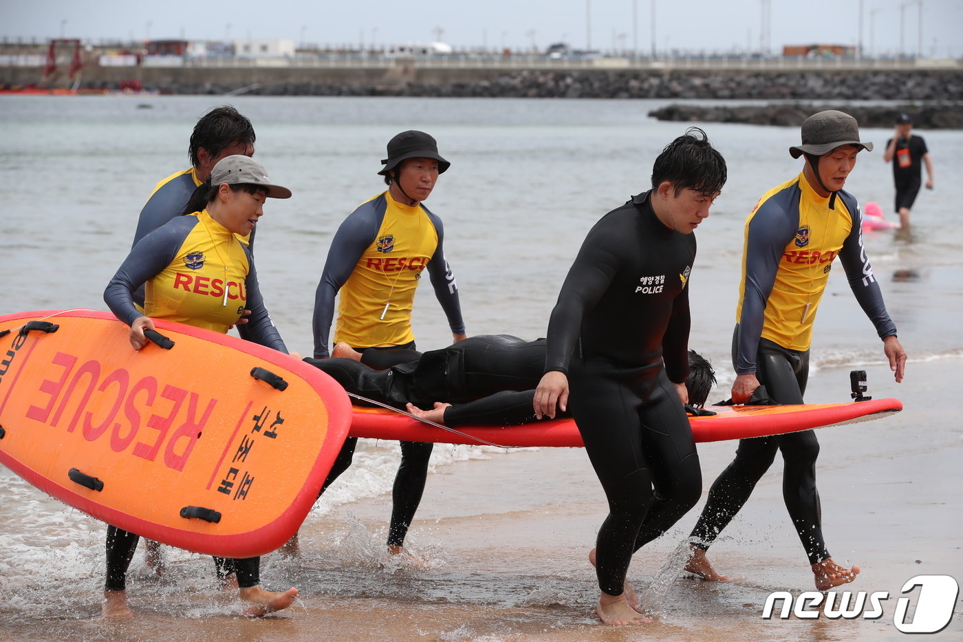 본문 이미지 - 24일 오전 제주시 이호 제주시 이호테우해수욕장에서 열린 서프구조대 발대식과 민간구조경진대회에 앞서 제주해경과 서프구조대의 민관합동 해상구조 시연에서 해경과 민간 서프구조대원들이 익수자 구조에 성공, 물 밖으로 나오고 있다.2023.6.24/뉴스1