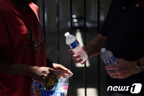 27일(현지시간) 미국 텍사스주(州) 휴스턴에서 자선단체 회원이 노숙자들에게 물을 나눠주고 있다. 2023.06.27/ © 로이터=뉴스1 © News1 권진영 기자