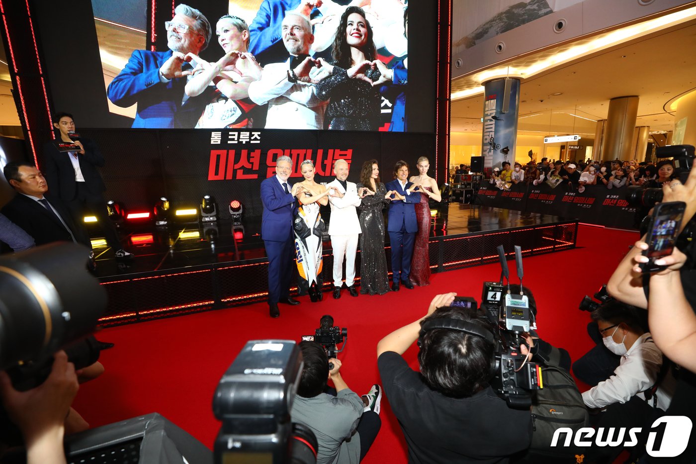 본문 이미지 - 크리스토퍼 맥쿼리 감독(왼쪽부터)과 할리우드 배우 폼 클리멘티에프, 사이먼 페그, 헤일리 앳웰, 톰 크루즈, 바네사 커비가 29일 서울 송파구 롯데시네마 월드타워점에서 열린 영화 '미션 임파서블: 데드 레코닝 파트 원' 레드카펫 행사에서 체인 하트를 그리고 있다. ⓒ News1 권현진 기자