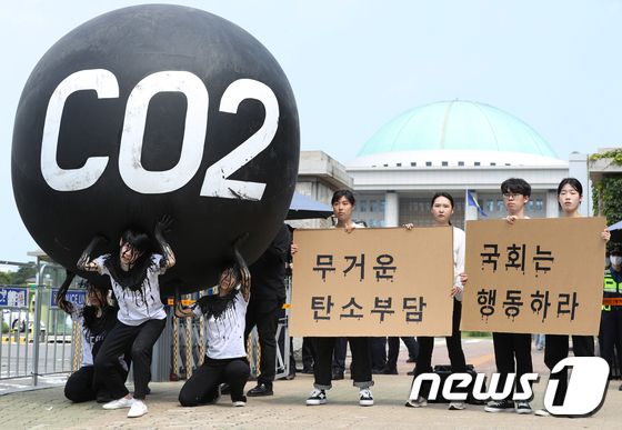 그린피스 회원들이 세계 환경의 날인 5일 서울 여의도 국회 앞에서 기후위기 대응을 촉구하는 '탄소(CO2)의 짐' 퍼포먼스를 하고 있다. 2023.6.5/뉴스1 © News1 신웅수 기자