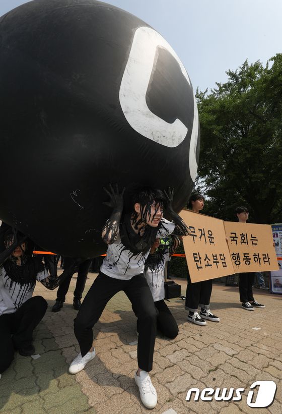 그린피스 회원들이 세계 환경의 날인 5일 서울 여의도 국회 앞에서 기후위기 대응을 촉구하는 '탄소(CO2)의 짐' 퍼포먼스를 하고 있다. 2023.6.5/뉴스1 © News1 신웅수 기자