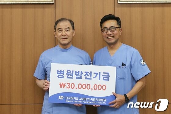 홍찬의 석좌교수(왼쪽)가 정동화 단국대 죽전치과병원장에게 발전기금을 전달하고 있다.(단국대 제공)