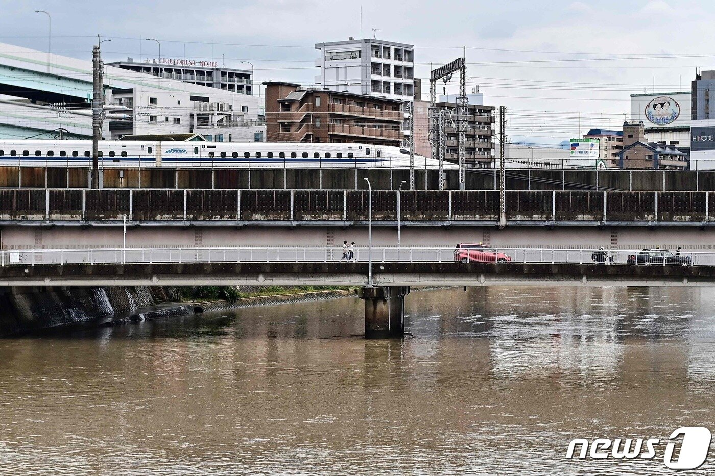 본문 이미지 - 10일 일본 후쿠오카시(市) 폭우로 불어난 미가사강 위를 신칸센 고속열차가 지나가고 있다. 2023.07.10/ ⓒ AFP=뉴스1 ⓒ News1 권진영 기자