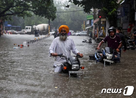 8일(현지시간) 인도 뉴델리에서 빗물로 잠긴 도로를 한 남성이 오토바이를 끌고 지나가고 있다. 2023.07.08/ © 로이터=뉴스1 © News1 권진영 기자
