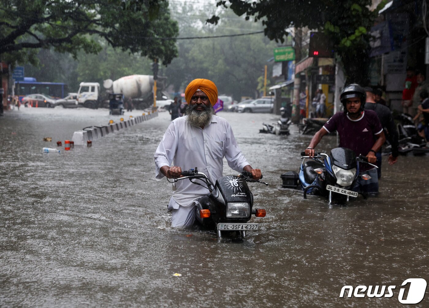 본문 이미지 - 8일(현지시간) 인도 뉴델리에서 빗물로 잠긴 도로를 한 남성이 오토바이를 끌고 지나가고 있다. 2023.07.08/ ⓒ 로이터=뉴스1 ⓒ News1 권진영 기자