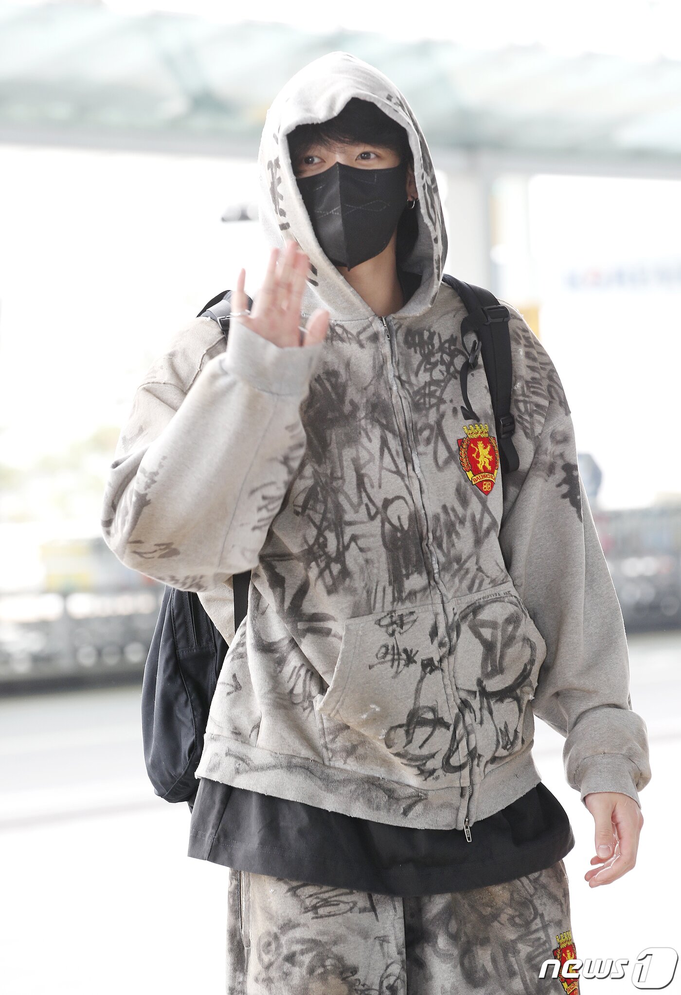 본문 이미지 - 방탄소년단(BTS) 정국이 해외 일정을 위해 12일 미국 뉴욕으로 출국하며 손 인사를 하고 있다. ⓒ News1 권현진 기자