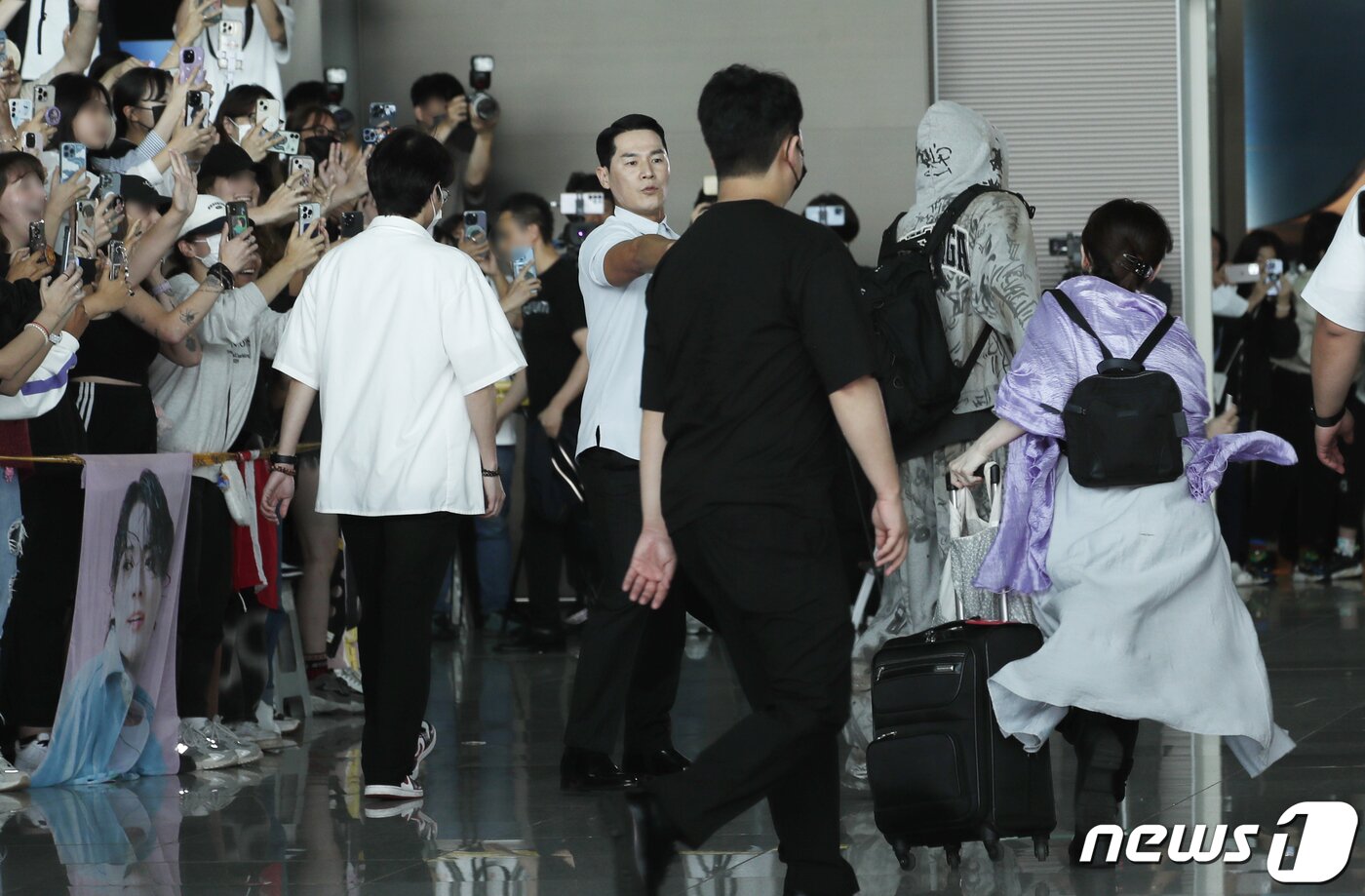 본문 이미지 - 12일 인천국제공항에서 미국 뉴욕으로 출국하는 방탄소년단 정국을 가까이에서 보기 위해 보라색 의상을 입은 한 팬이 라인을 무시하고 정국에게 달려들고 있다.  ⓒ News1 권현진 기자