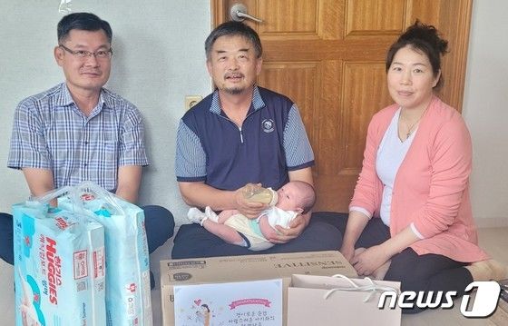 이재영 응봉면장(왼쪽)이 다섯째 아기를 안고 있는 장성희(52)·강미선(44)씨 부부 가정을 방문해 축하를 전하고 있다.(예산군 제공)/뉴스1