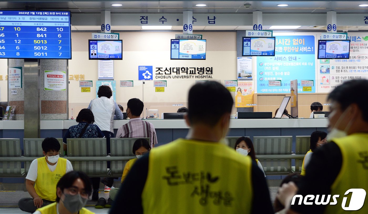 전국보건의료산업노동조합이 총파업에 돌입한 13일 오전 광주 동구 조선대학교 병원 로비에서 노조원들이 농성을 하고 있는 가운데 환자들이 진료를 위해 대기하고 있다. 2023.7.13/뉴스1 ⓒ News1 이승현 기자