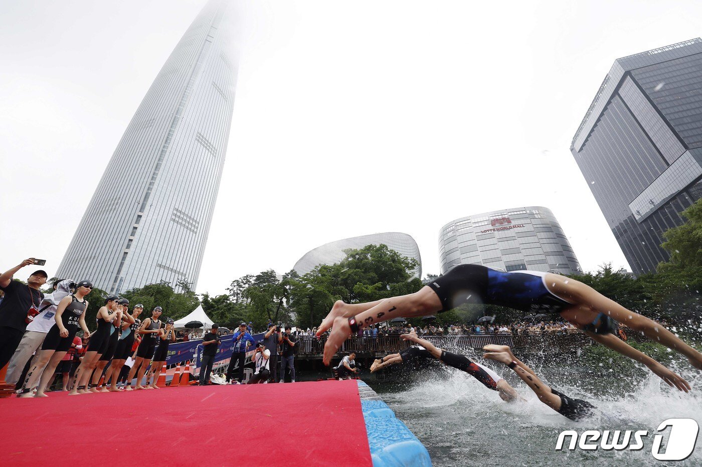 본문 이미지 - 16일 오전 서울 송파구 롯데월드타워 일대에서 열린 '2023 롯데 아쿠아슬론 대회'에 출전한 참가자들이 석촌호수에서 수영하고 있다. 2023. 07. 16 ⓒ News1 신웅수 기자