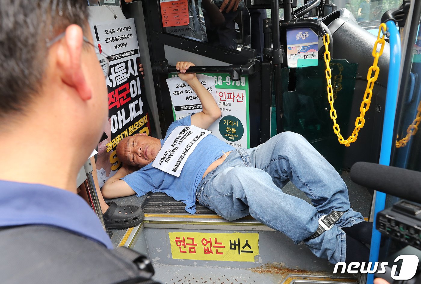 본문 이미지 - 전국장애인차별철폐연대(전장연) 회원들이 17일 오후 서울 종로구 혜화동로터리 버스 정류장에서 전장연 탄압 중단을 촉구하며 '계단 버스' 탑승을 시도하고 있다. 2023.7.17/뉴스1 ⓒ News1 김진환 기자