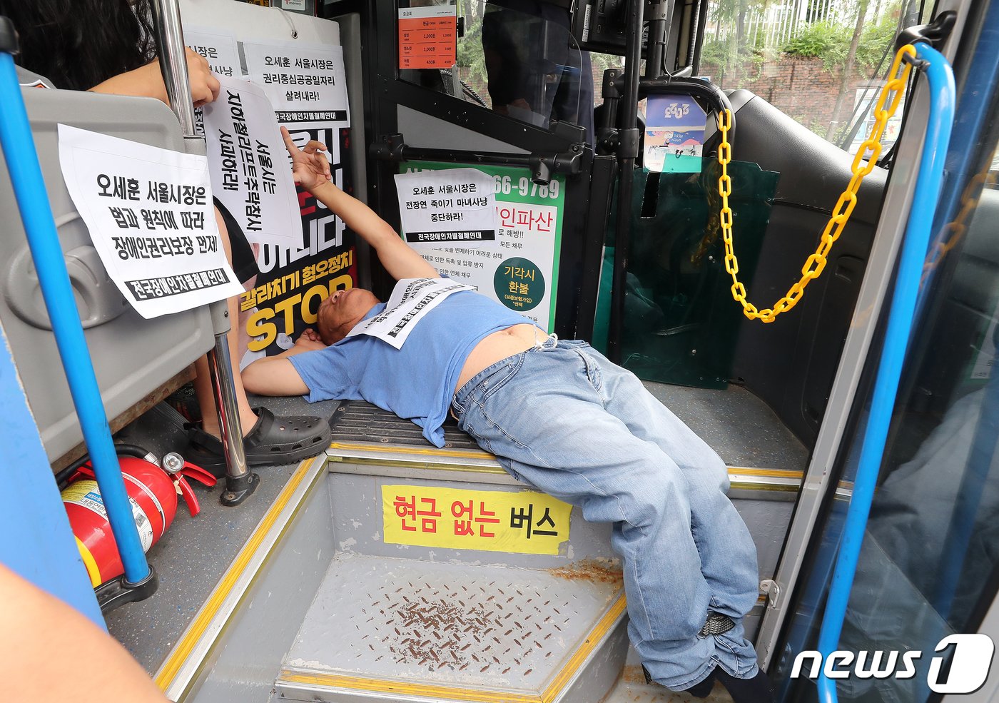 본문 이미지 - 전국장애인차별철폐연대(전장연) 회원들이 17일 오후 서울 종로구 혜화동로터리 버스 정류장에서 전장연 탄압 중단을 촉구하며 '계단 버스' 탑승을 시도하고 있다. 2023.7.17/뉴스1 ⓒ News1 김진환 기자