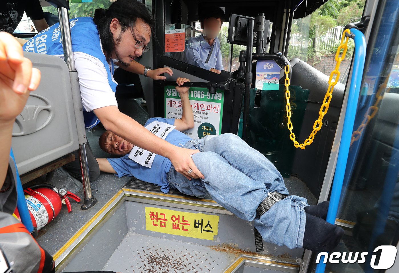 본문 이미지 - 전국장애인차별철폐연대(전장연) 회원들이 17일 오후 서울 종로구 혜화동로터리 버스 정류장에서 전장연 탄압 중단을 촉구하며 '계단 버스' 탑승을 시도하고 있다. 2023.7.17/뉴스1 ⓒ News1 김진환 기자
