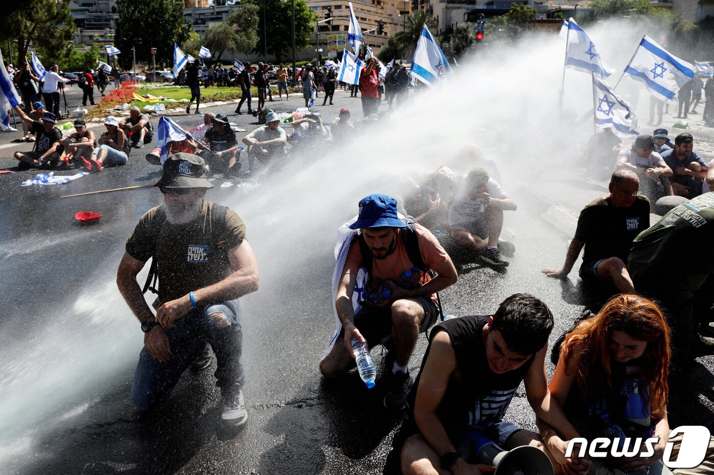 본문 이미지 - 24일(현지시간) 예루살렘에서 베냐민 네타냐후 이스라엘 총리와 우파 연정이 강행 중인 사법 개편안에 반대하는 시위가 벌어지는 동안 시위대가 물대포를 맞고 있다. 2023.07.24/뉴스1 ⓒ 로이터=뉴스1 ⓒ News1 김민수 기자