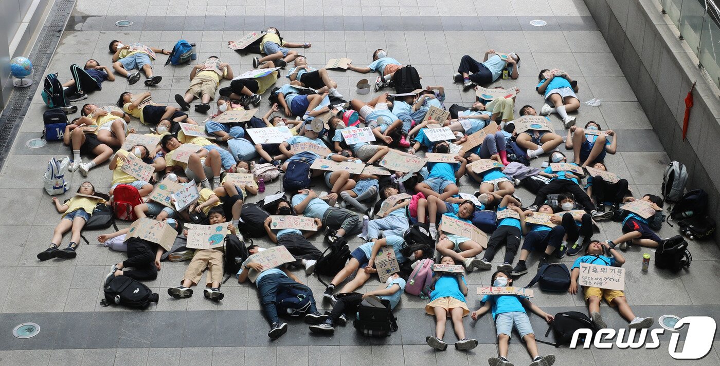 본문 이미지 - 수원시청에서 신영초등학교 4학년 학생들이 기후 위기 대응을 촉구하며 다이인(Die-in) 퍼포먼스를 하고 있다. (자료사진) 2023.7.5/뉴스1 ⓒ News1 김영운 기자