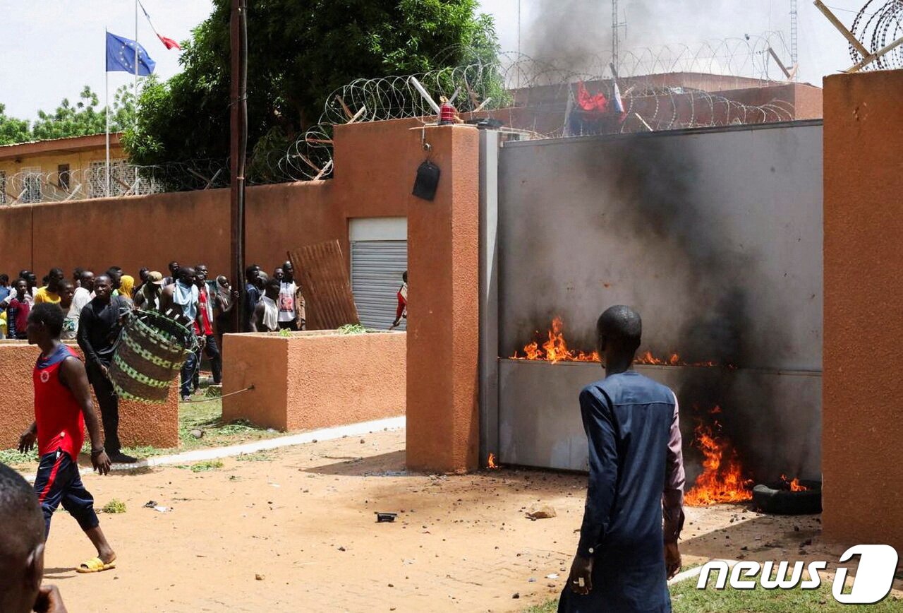 본문 이미지 - 30일(현지시간) 서아프리카 니제르의 수도 니아메에서 니제르 쿠데타를 주도한 군부 세력의 지지자들이 프랑스 대사관 밖에서 시위하며 정문에 불을 지르고 있다. 2023.07.30/ ⓒ 로이터=뉴스1 ⓒ News1 박재하 기자