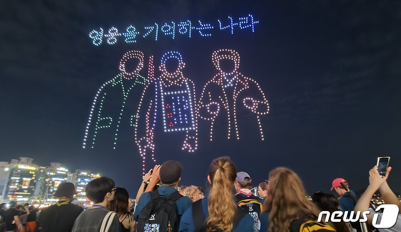 본문 이미지 - 12일 부산 수영구 광안리해수욕장을 찾은 잼버리 대원들이 광복절을 주제로하는 '드론 M 라이트쇼'를 보고 있다.2023.8.12/뉴스1 ⓒ News1 조아서 기자