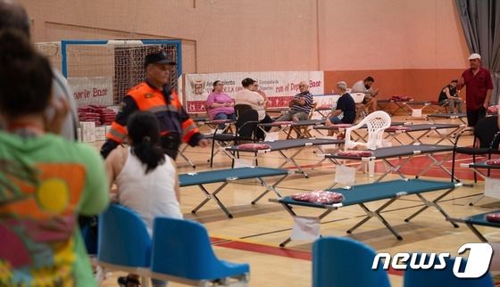 17일(현지시간) 스페인 카나리아섬 테네리페에서 주민들이 지난 15일 발생한 산불을 피해 대피소에 모여 있다. 주황색 조끼를 입은 적십자 대원이 현장을 확인하고 있다. 2023.08.17/ © AFP=뉴스1 © News1 권진영 기자