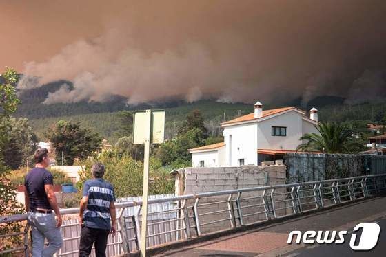17일(현지시간) 스페인의 휴양지 테네리페섬에서 두 사람이 솟구치는 산불 연기를 바라보고 있다. © AFP=뉴스1 © News1 권진영 기자