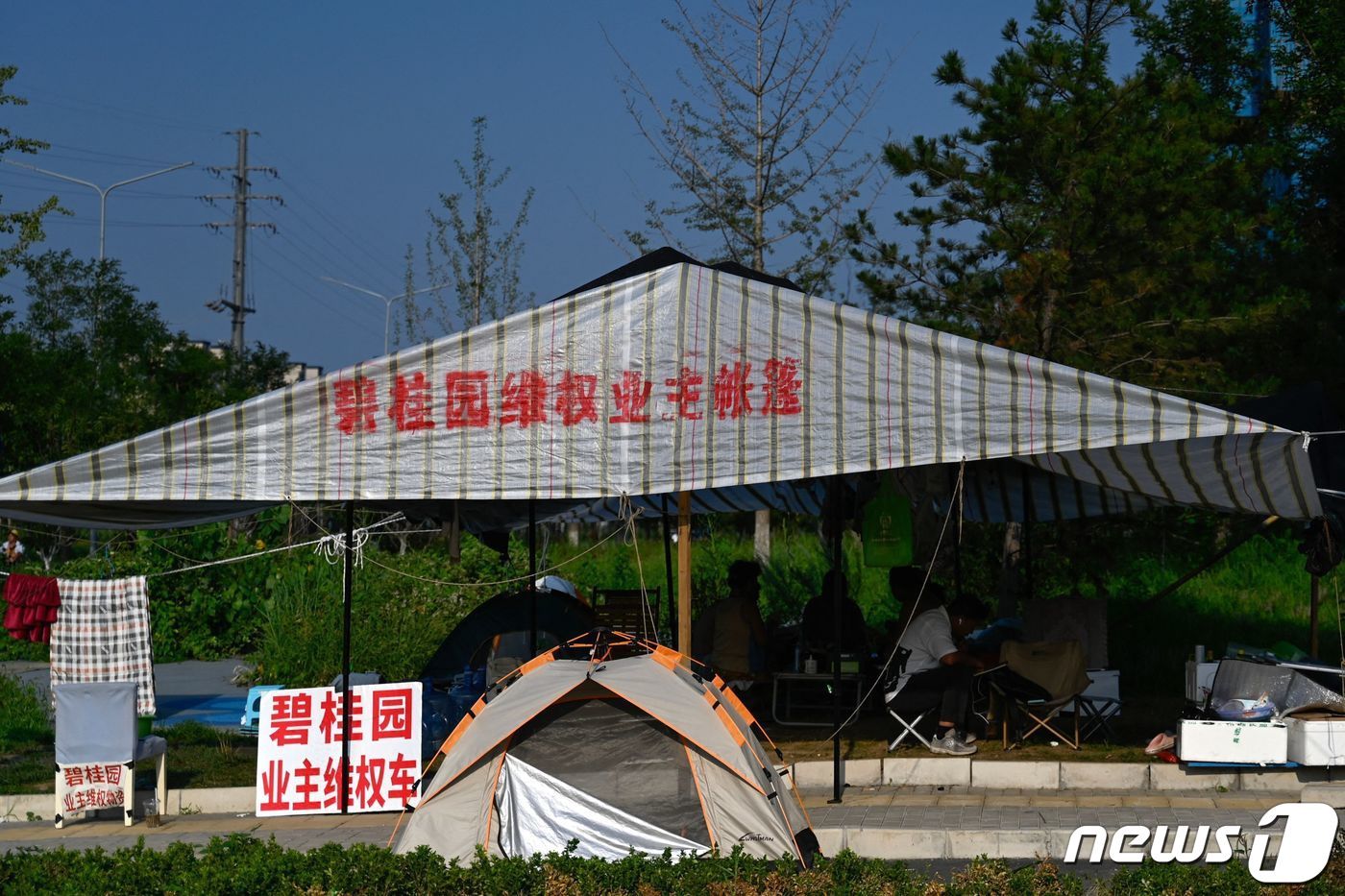 15일 베이징의 최근 디폴트 위기를 맞고 있는 컨트리 가든 공사 현장 옆에서 주민들이 항의 농성을 벌이고 있다. ⓒ AFP=뉴스1 