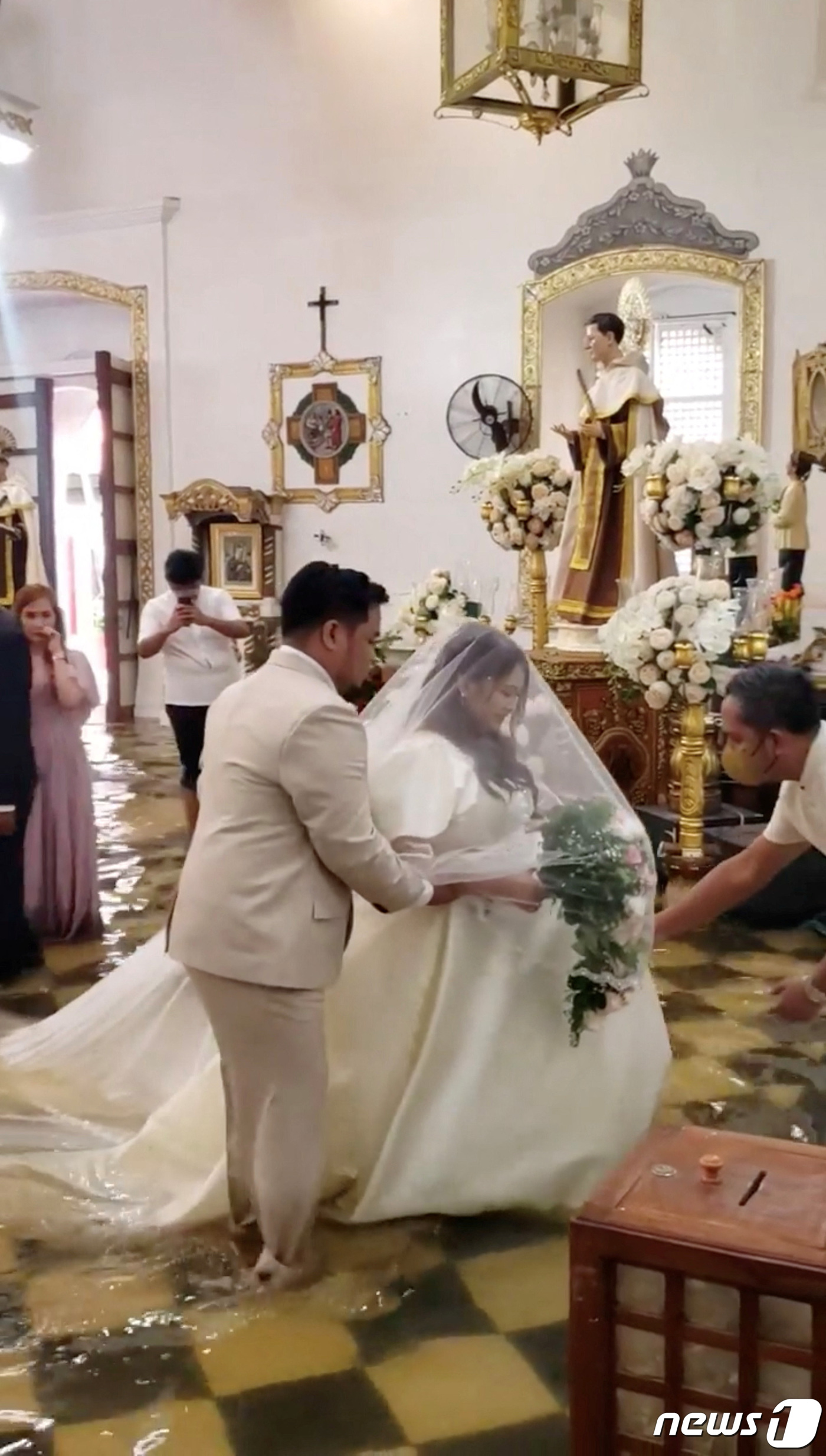 (말롤로스 로이터=뉴스1) 우동명 기자 = 30일 (현지시간) 태풍 독수리가 강타해 폭우가 쏟아진 필리핀 말롤로스의 물이 흥건한 교회에서 신부가 드레스를 입고 걸어 가고 있다. 2 …