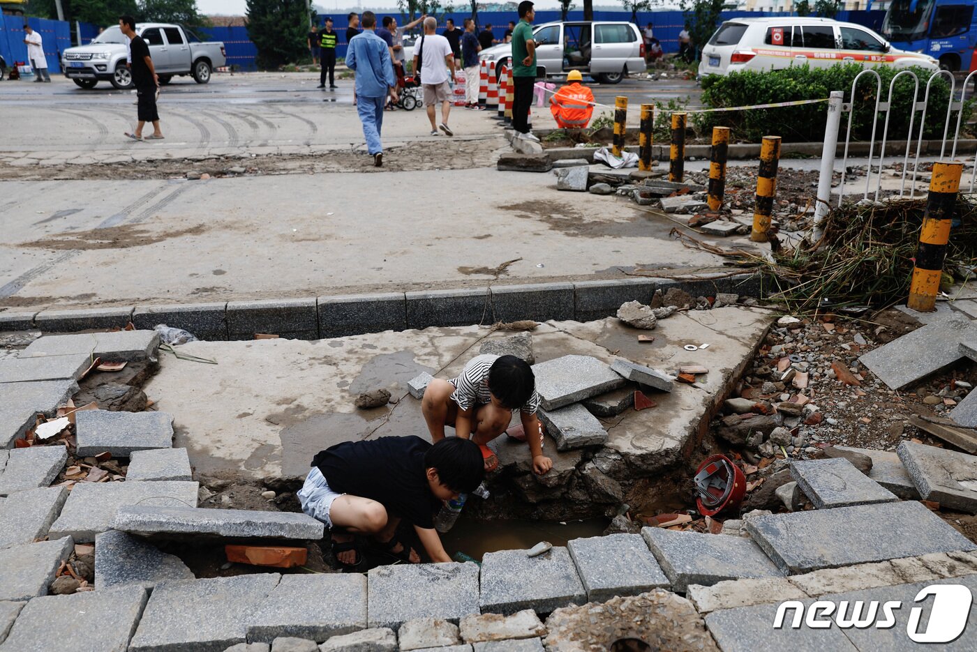 본문 이미지 - 2일 (현지시간) 태풍 '독수리'가 휩쓸고 간 중국 베이징의 거리에 발생한 큰 구멍을 둘러 싸고 어린이들이 놀고 있다. 2023.8.2 ⓒ 로이터=뉴스1 ⓒ News1 우동명 기자