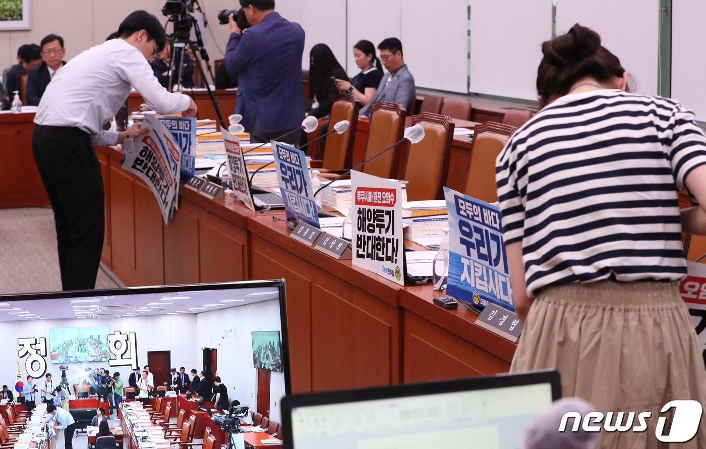 본문 이미지 - 23일 서울 여의도 국회에서 열린 외교통일위원회 전체회의에서 관계자들이 더불어민주당 의원석의 '후쿠시마 오염수 해양투기 반대' 등의 문구가 적힌 피켓을 떼고 있다. 이날 국회 외통위는 더불어민주당 의원들의 후쿠시마 오염수 방류 반대 피켓으로 회의가 지연됐다. 2023.8.23/뉴스1 ⓒ News1 송원영 기자