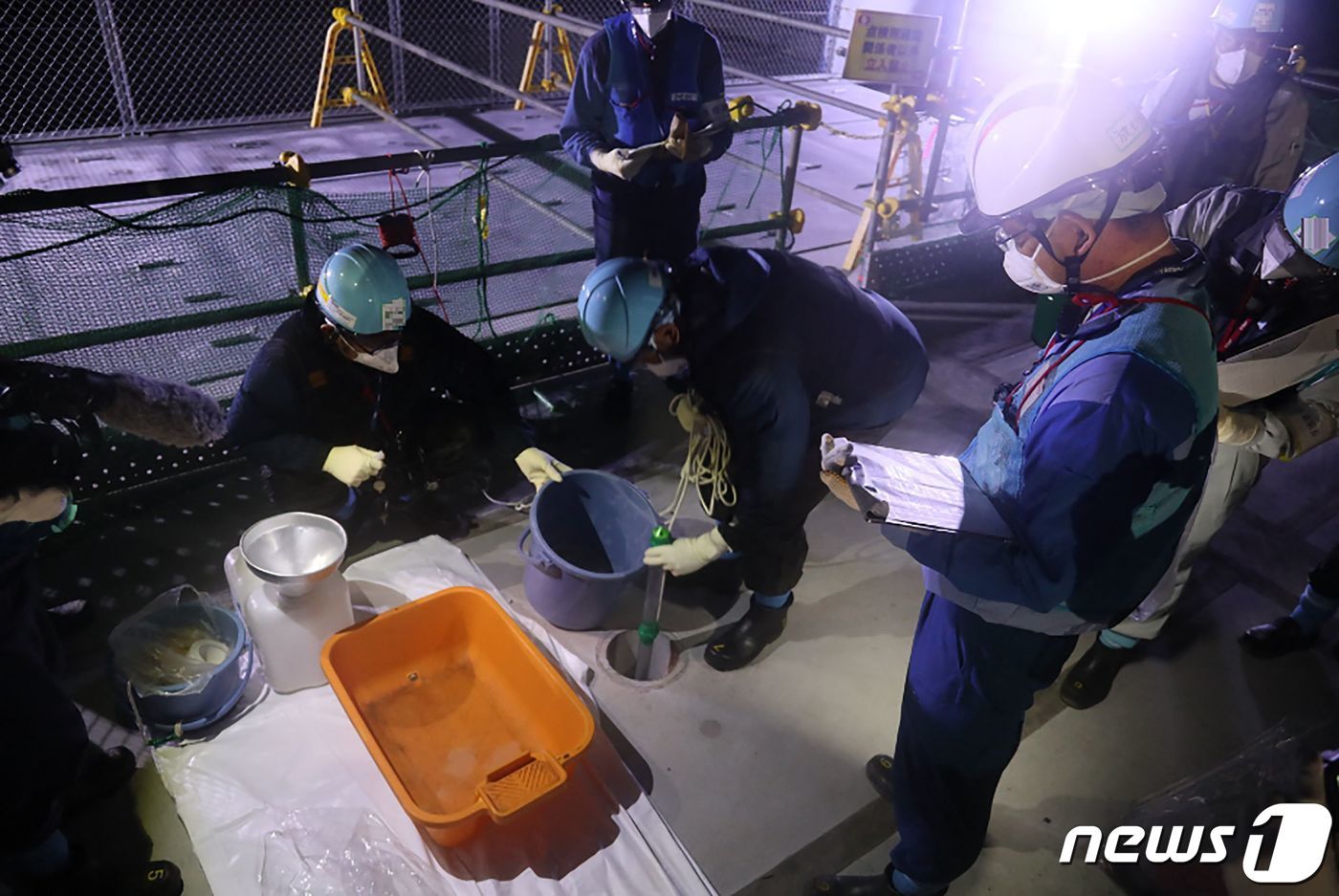 본문 이미지 - 22일 일본 후쿠시마 제1 원자력발전소에서 도쿄전력 직원들이 희석한 방사능 오염수 샘플을 채취하고 있다. 2023.08.22/ ⓒ AFP=뉴스1 ⓒ News1 권진영 기자