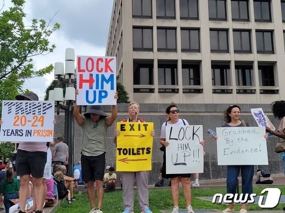도널드 트럼프 전 대통령을 비판하는 시위대가 3일(현지시간) 워싱턴DC 연방 지방법원 앞에서 트럼프 전 대통령을 가둬야 한다는 문구가 적힌 피켓을 들고 시위를 하고 있다.