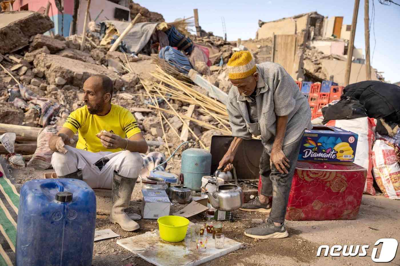 10일(현지시간) 모로코에서 자원봉사자들이 무너진 잔해 옆에서 식사를 하고 있다. 2023.09.11/ © AFP=뉴스1 © News1 홍유진 기자