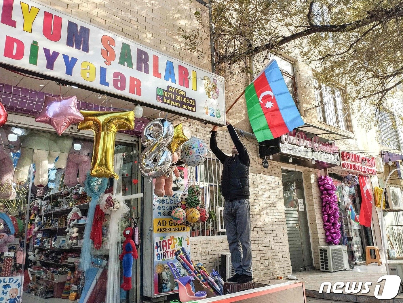 본문 이미지 - 20일&#40;현지시간&#41; 아제르바이잔 수도 바쿠에서 한 주민이 나고르노-카라바흐 지역에서 국가의 공세를 지지하는 뜻으로 가게 앞에 국기를 걸고 있다. 23.09.20 ⓒ AFP=뉴스1 ⓒ News1 김예슬 기자