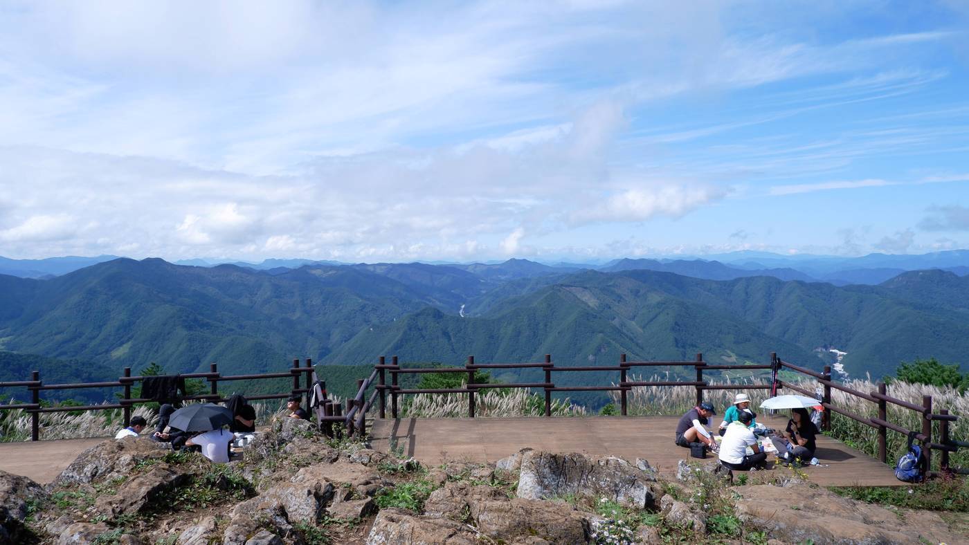 본문 이미지 - 정상에서 끝없이 펼쳐지는 능선을 배경 삼아 쉬고 있는 등산객들. ⓒ News1 