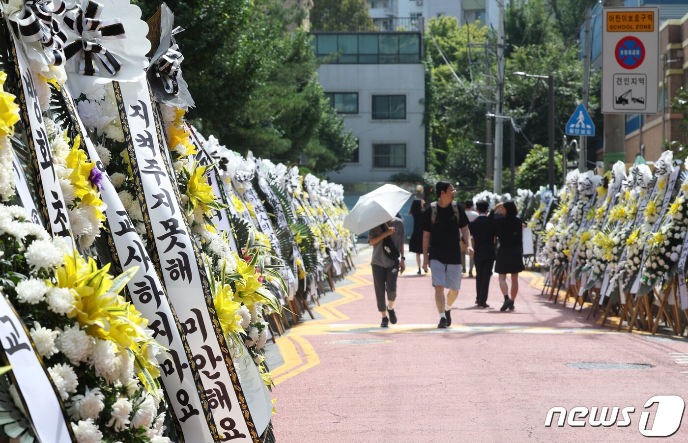 본문 이미지 - 3일 서울 양천구의 한 초등학교에 마련된 교사 A씨의 추모공간을 찾은 추모객들이 근조 화환을 보고 있다. 올해로 14년차 교사인 A씨는 지난달 31일 경기 고양시의 한 아파트에서 극단적 선택으로 숨졌다. 2023.9.3/뉴스1 ⓒ News1 신웅수 기자