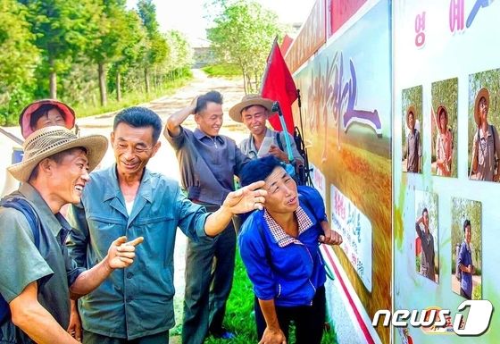 '영예 혁신자' 게시판 보고 있는 북한 농장원들