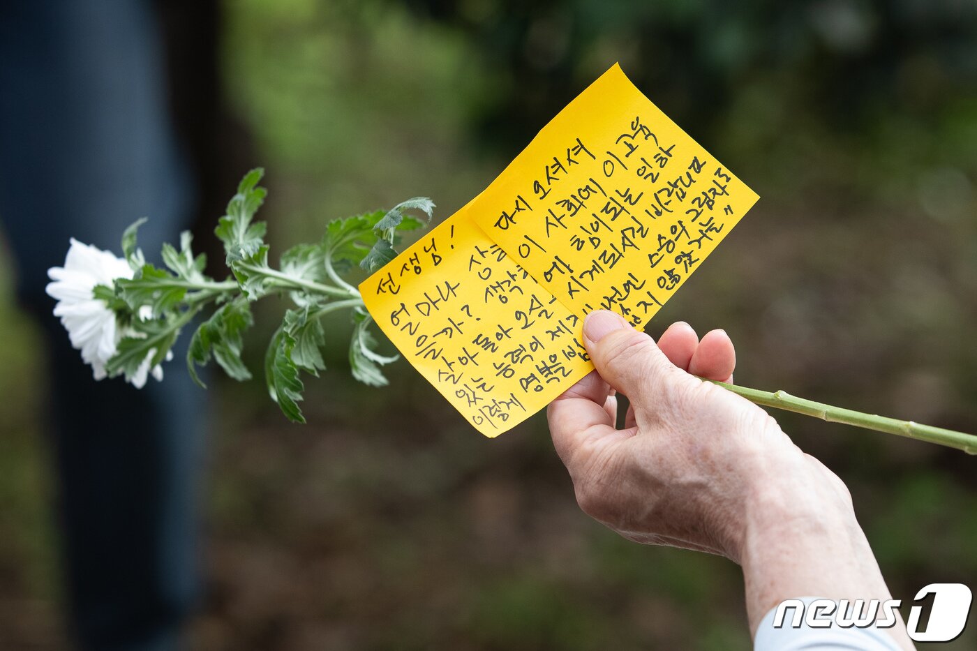 본문 이미지 - 서울 서이초 사망 교사의 49재인 4일 서울 서초구 서이초등학교에 마련된 추모공간을 찾은 한 추모객의 손에 국화와 추모문구가 들려 있다. 2023.9.4/뉴스1 ⓒ News1 유승관 기자