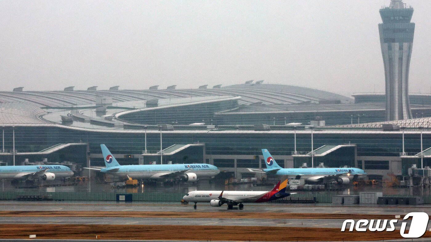 본문 이미지 - 인천국제공항 계류장에 세워진 대한항공 항공기 앞으로 아시아나 항공기가 이륙하고 있다. 2024.1.14/뉴스1 ⓒ News1 장수영 기자