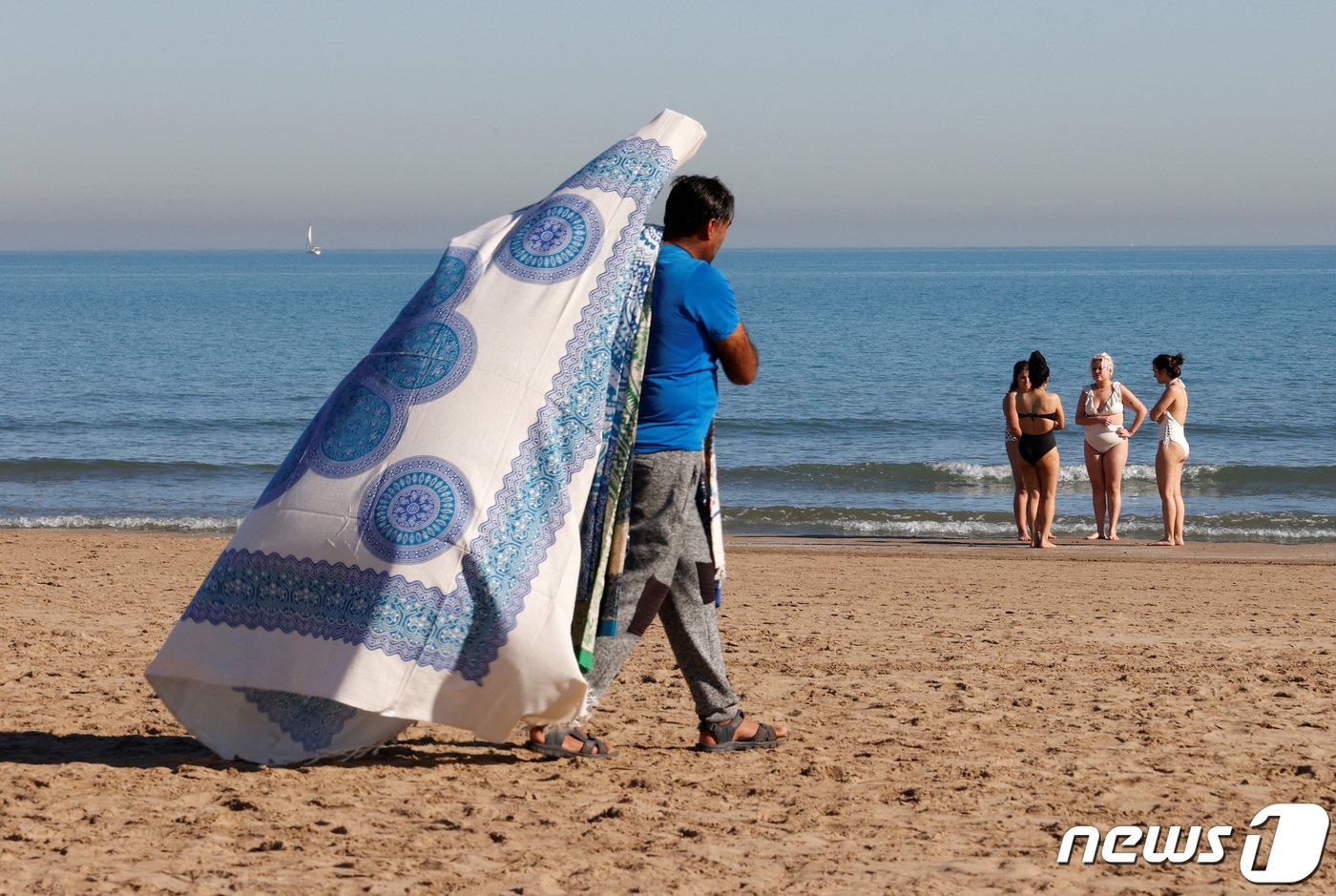 본문 이미지 - 무더위가 찾아오면서 해변가가 북적이자 한 돗자리 상인이 돗자리를 들고 이동하고 있다. 2024.01.25 ⓒ 로이터=뉴스1 ⓒ News1 정지윤 기자