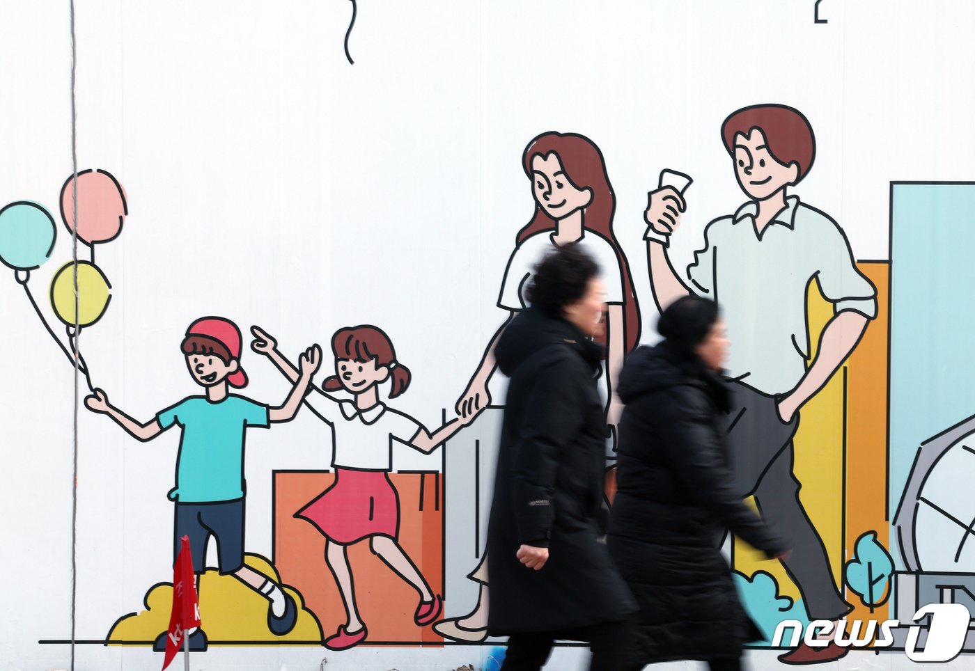 본문 이미지 - 신생아 특례대출 신청이 시작된 29일 서울 도심의 공사장 가림막에 그려진 행복한 가족 그림 앞으로 시민들이 지나고 있다.  2024.1.29/뉴스1 ⓒ News1 박정호 기자