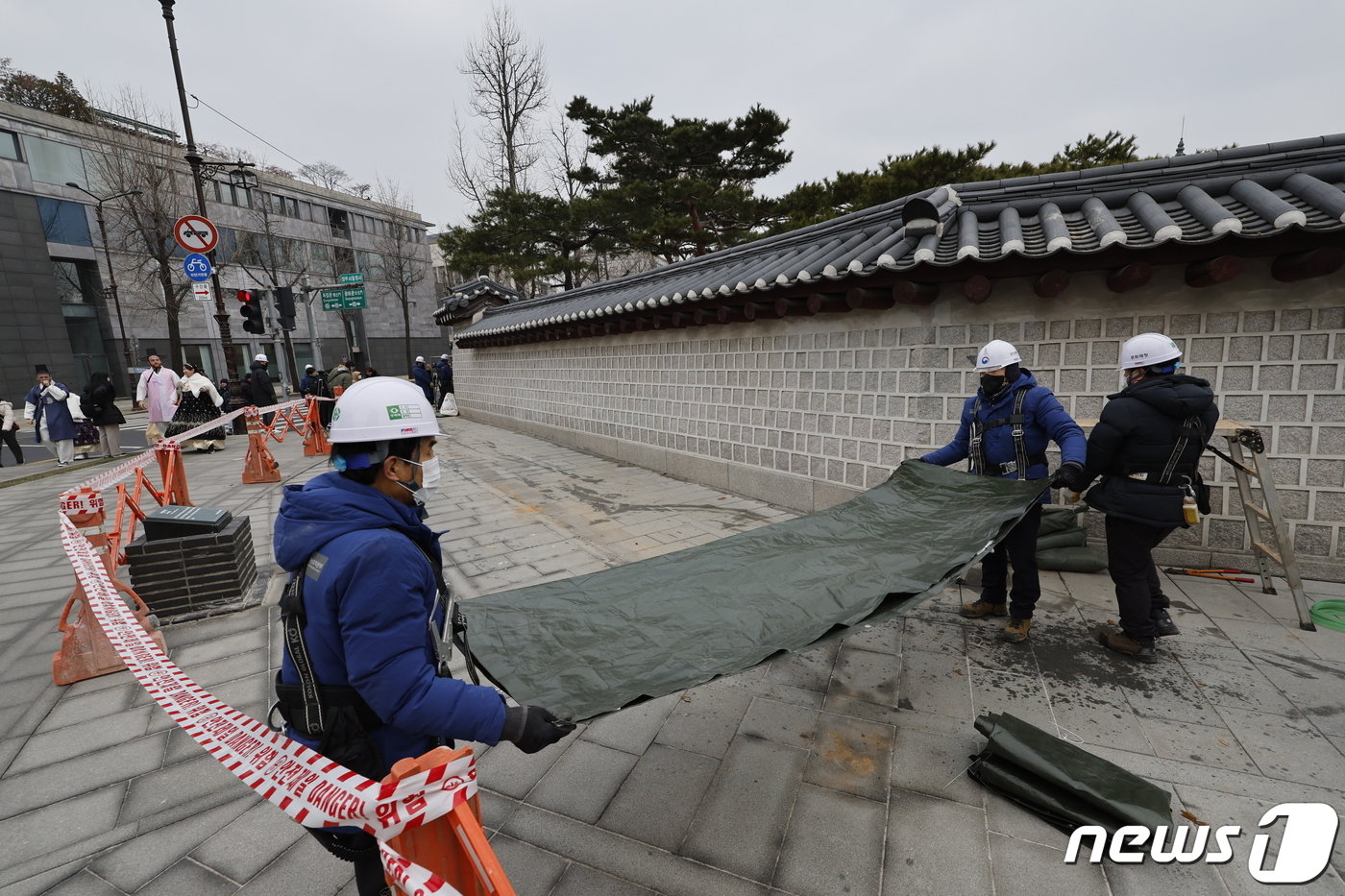 본문 이미지 - 4일 서울 종로구 경복궁에서 담장 낙서 제거 작업을 마친 문화재청 관계자들이 가림막을 철거한 뒤 청소하고 있다. 2024.1.4/뉴스1 ⓒ News1 안은나 기자