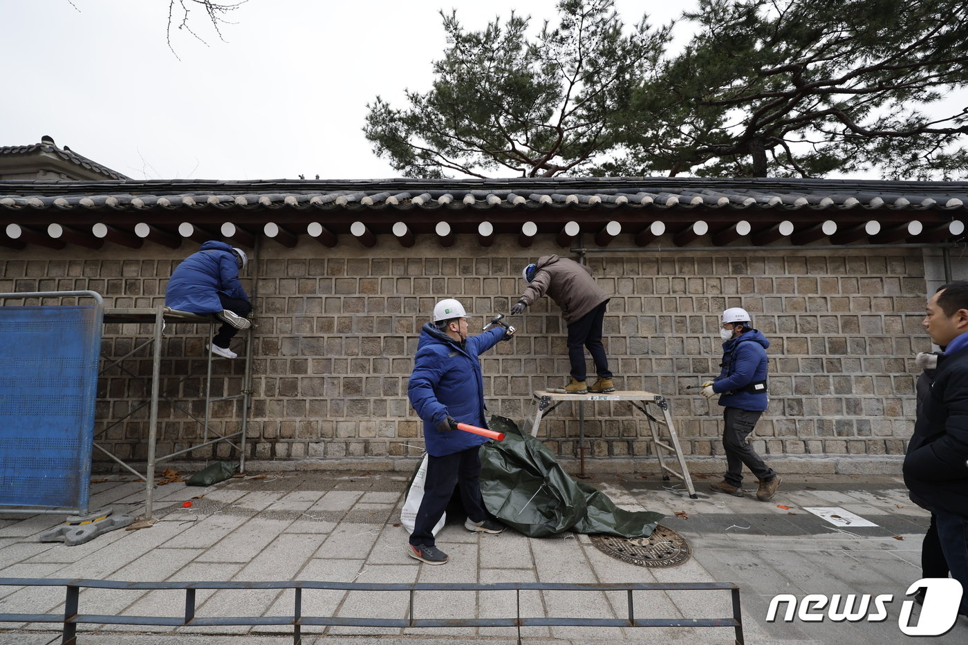 본문 이미지 - 4일 서울 종로구 경복궁에서 담장 낙서 제거 작업을 마친 문화재청 관계자들이 가림막을 철거한 뒤 청소하고 있다. 2024.1.4/뉴스1 ⓒ News1 안은나 기자