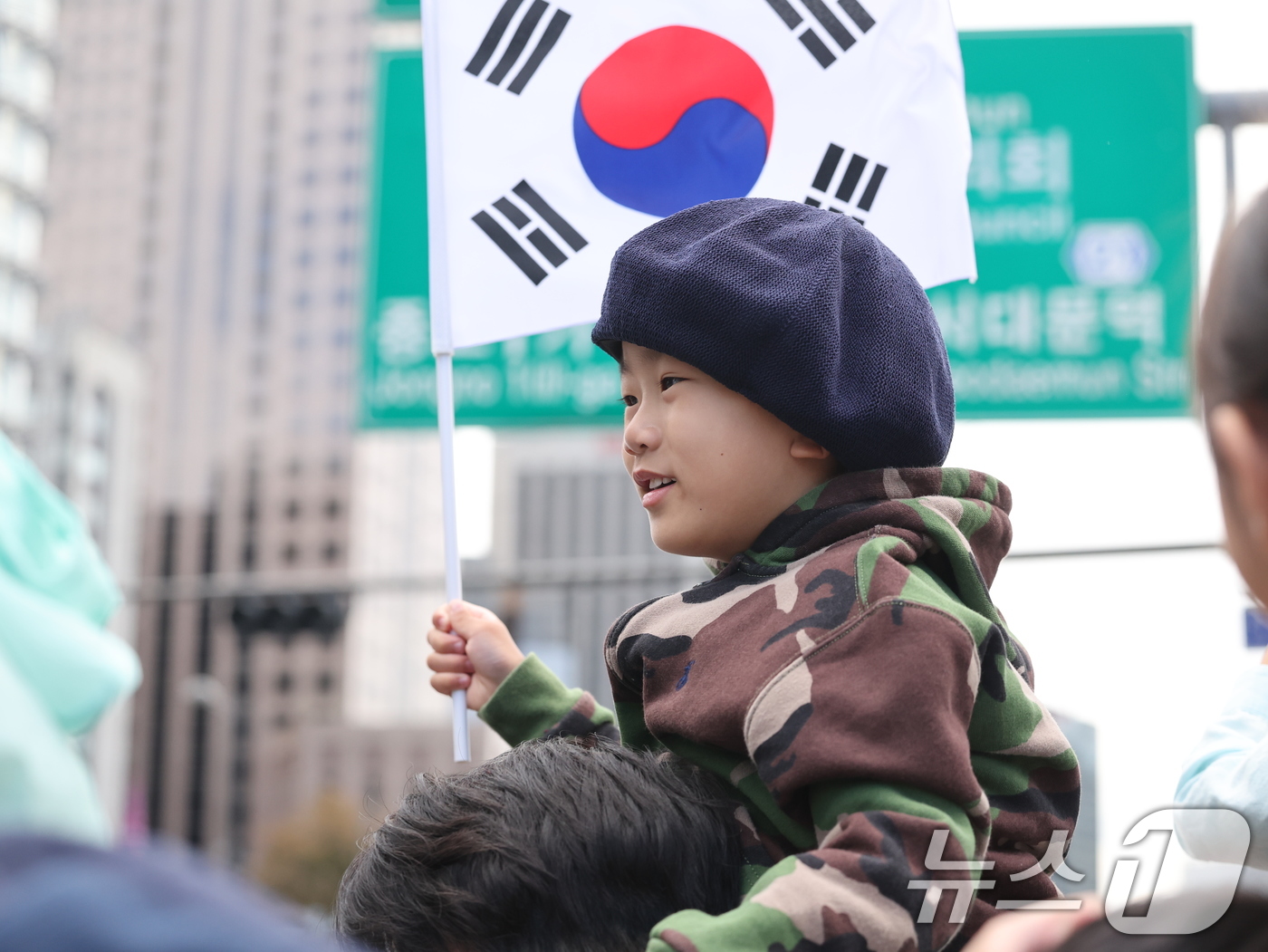 (서울=뉴스1) 황기선 기자 = 국군의 날인 1일 서울 종로구 광화문광장 일대에서 한 어린이가 태극기를 들고 ‘건군 76주년 국군의날 시가행진’을 보기 위해 목마를 탄채 기다리고 …